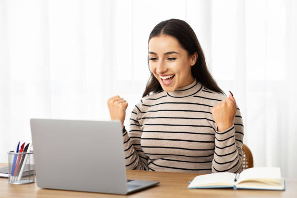 istock Glad young arab woman manager work at computer, celebrate win, success with raise hands 1994971809