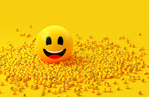 Yellow spheres textured with happy face emoji surrounded by other happy face emojis on yellow background. Horizontal composition.