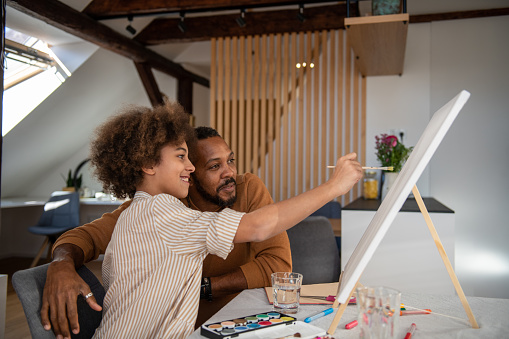 Father and daughter painting at home