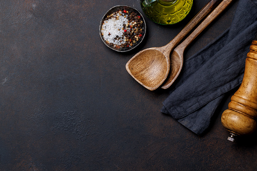 Culinary essentials: Diverse cooking utensils and spices on stone table. Flat lay with copy space