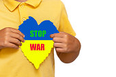 Inscription STOP WAR.Boy holding flag of Ukraine with the heart shape symbol.On the white isolated background.Selective focus.