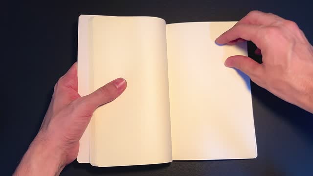 Human hands slowly leafing through the blank pages of a book