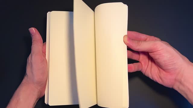 Human hands quickly leafing through the blank pages of a book