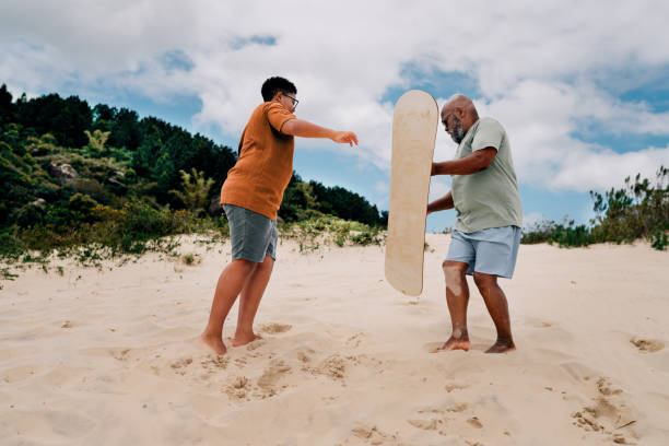 istock Dad and his son learning to sandboard during summer vacation 1995007531