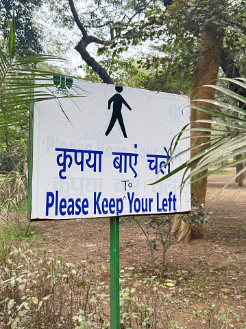 Stock photo showing close-up view of a rectangular, 'please keep to your left' sign in public park.