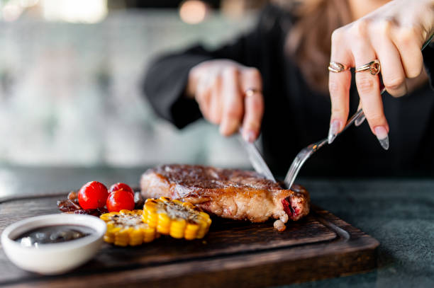 istock woman hands with fork and knife eating beef steak in cafe 1995022878