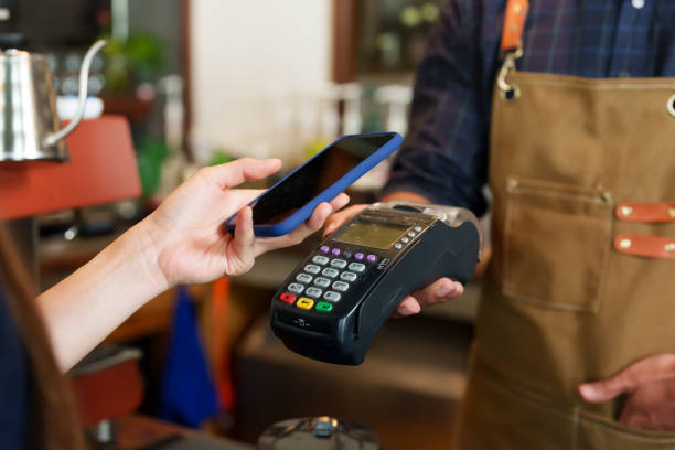 istock A beautiful Asian female customer comes use cafe holds cell phone scan the QR code At the card swiping machine owned barista shop young men various nationalities held inside small family-owned cafe 1995023389