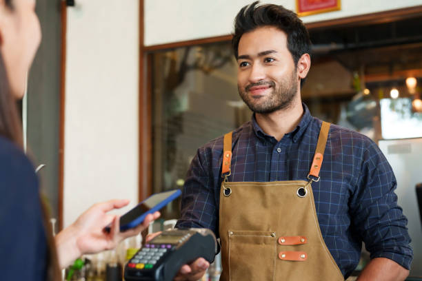 istock A beautiful Asian female customer comes use cafe holds cell phone. to scan QR code card machine owned barista shop young men various nationalities smiled each other held inside small business cafe. 1995023393