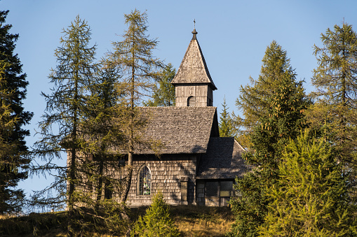 View of the Nassfeld Memorial Chapel at the austrian border to Italy, surrounded by trees with a blue sky