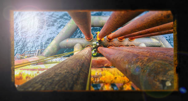 View true window on two industrial climbers making paint repairs on oil rig over sea. Extreme dangerous job. Denmark. North Sea. View true window on two industrial climbers making paint repairs on oil rig over sea. Extreme dangerous job. north sea oil and gas stock pictures, royalty-free photos & images