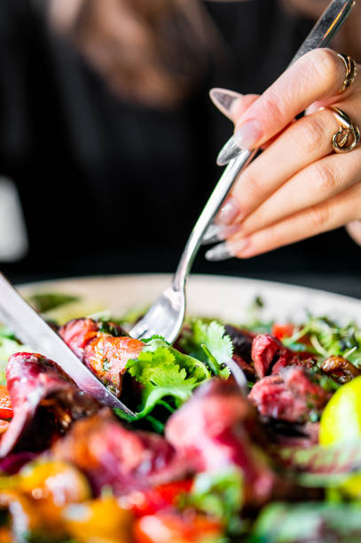 istock woman hands with knife and fork eat Fresh salad with 1995047723