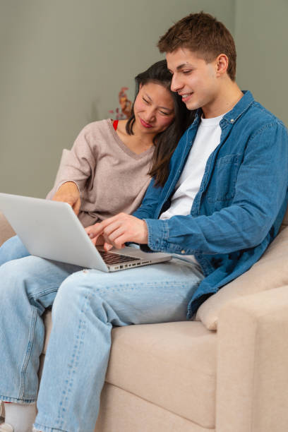 istock Happy multiethnic man and woman have fun browsing internet on laptop. Technology concept .Vertical 1995054112