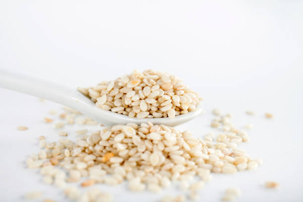 close-up of sesame seeds in a white ceramic spoon - sesame seed spoon scoop imagens e fotografias de stock