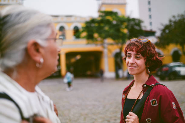 Smiling young woman and her mature mother standing together in a cobblestone square while exploring Municipal Market in Florianopolis, Brazil