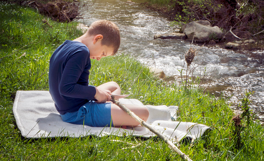 Little boy using knife in nature