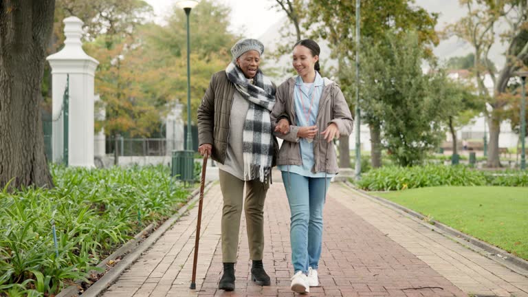 Help, cane and nurse with old woman in park for relax, support and person with a disability. Elderly care, conversation and healthcare with caregiver and patient in nature for medical rehabilitation