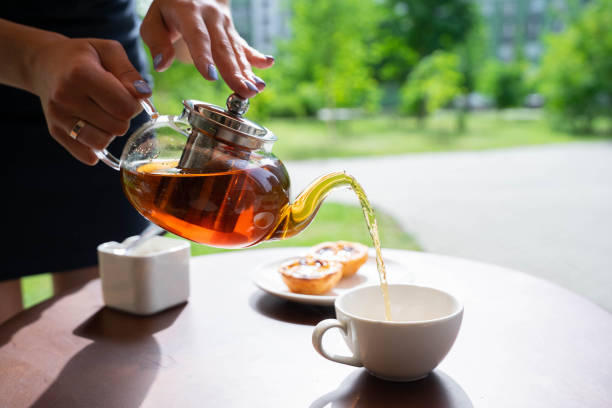 istock waitress pours tea into a cup next to cakes and sugar at caffe terrace in summer or spring 1995127252