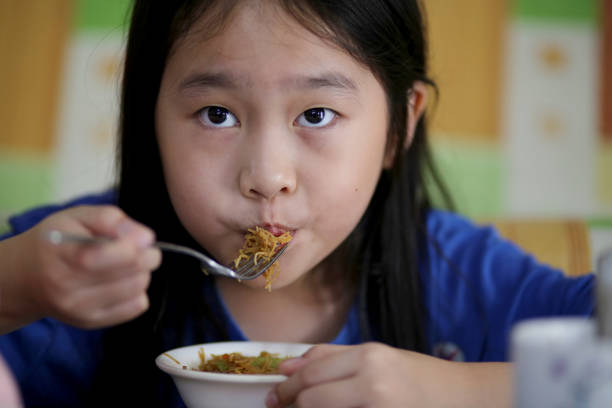 Portrait of young Asian girl enjoying fried vermicelli at home