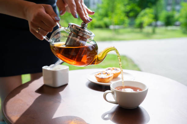 istock waitress pours tea into a cup next to cakes and sugar at caffe terrace in summer or spring 1995128896