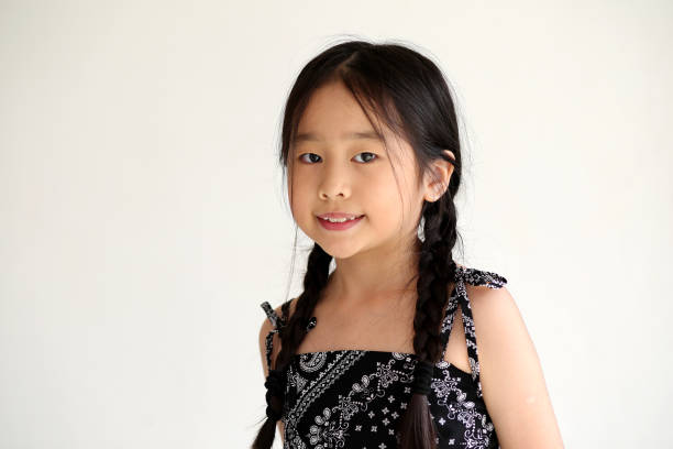Portrait of happy Asian young kid girl, confidently smiling showing mini heart sign with finger studio shot isolated on white background. Kindergarten child expressing love and joy for Valentine's Day