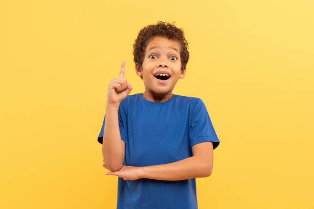 istock Excited boy with eureka moment, pointing up on yellow background 1995135678