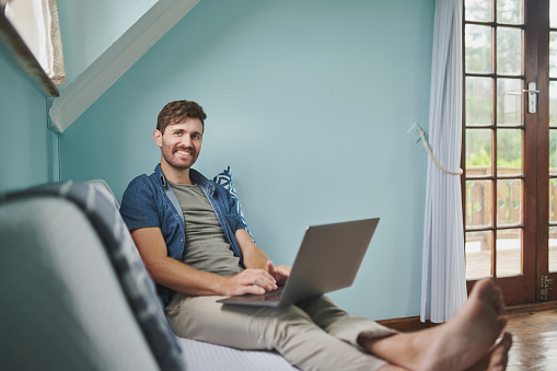 Streaming, movie and portrait of happy man with laptop on sofa in home to relax. Living room, computer and person smile with easy connection to online series, video on internet or watch show on web