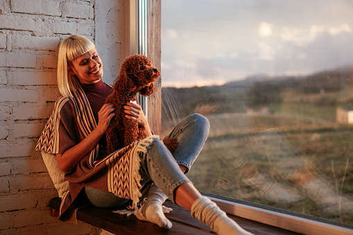 A young woman is enjoying her leisure time at home and bonding with her dog in the afternoon.