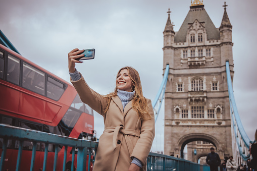 Happy tourist woman relaxing in London city at Westminster Big ben and red bus. Europe destination travel lifestyle.