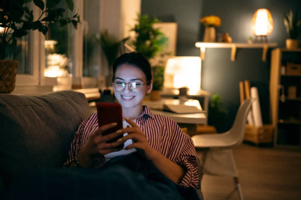 istock Young smiling woman using her phone during the relaxing evening at home 1995157848