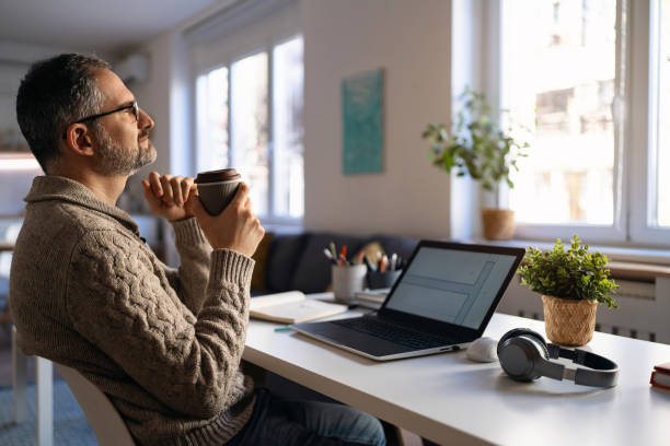 istock Mature Caucasian man enjoying first morning coffee while working from his home office 1995158426