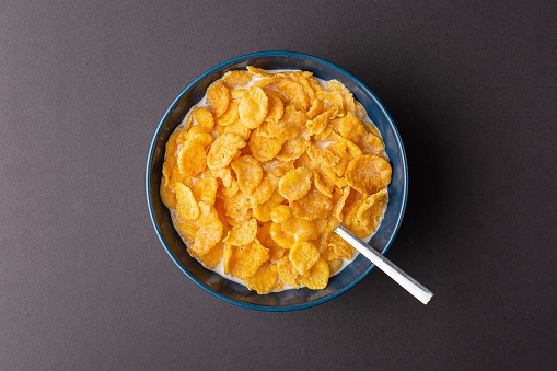 Cornflaskes bowl with a spoon on the dark background