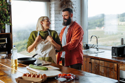 A happy Caucasian couple is at home cooking together in their stylish kitchen.