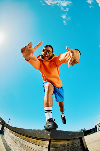 Gen Z teenager poses full body towards camera, showing attitude, shot wide angle against the sky.