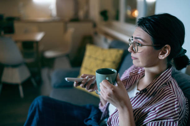 istock Young woman watching tv at home 1995170865