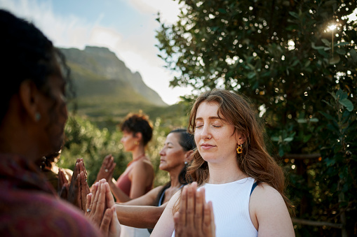Group of diverse women standing in pairs with their eyes closed and hands together during an exercise during a wellness retreat