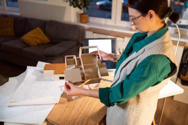 Young female architect making an architectural model in her home office