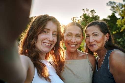 Smiling group of women taking a selfie together outside on a patio during a summer wellness retreat
