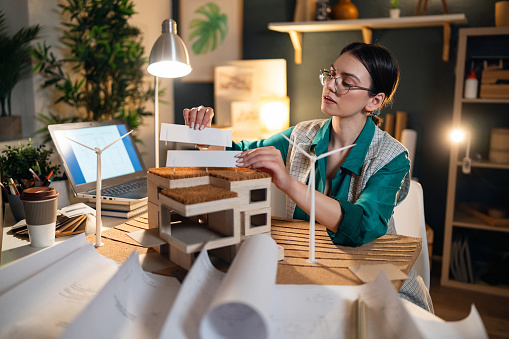 Young female architect making an architectural model in her home office.