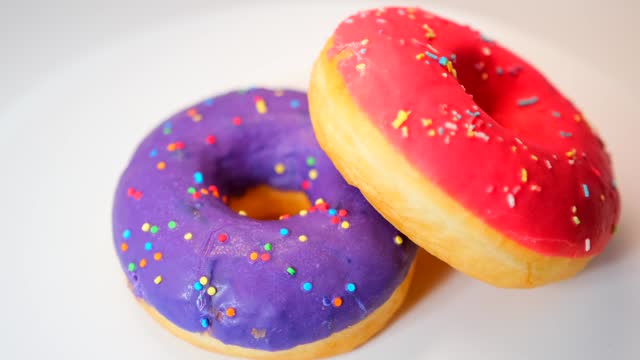 Donuts covered with lilac and pink glaze rotate in a circle on a white background