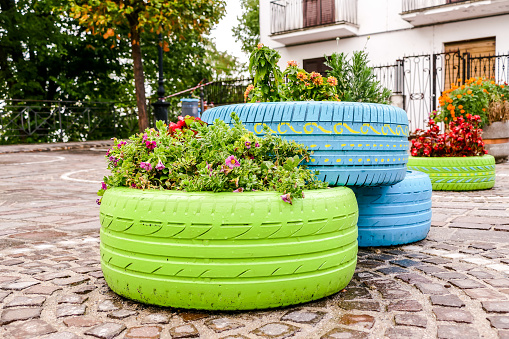 Old tires that are painted in assorted colors and used for a flower planter
