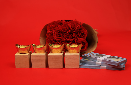 Model of Cash US dollars and  a bunch of red roses with a blank wooden block to inset the letter on Valentine's Day in a red background