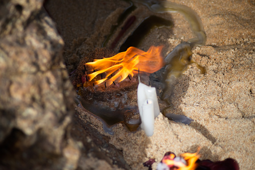 Candles burning among rocks on a beach to honor some religious entity. Salvador, Bahia.