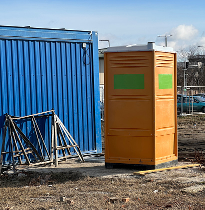 Portable toilet next to a container at the construction site
