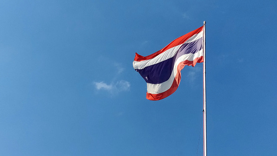 Flag waving proudly against a clear blue sky, symbolizing national of Thai