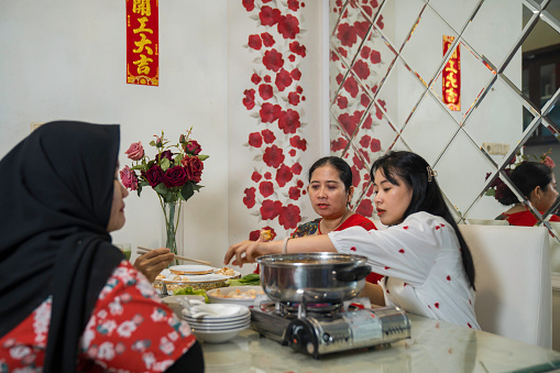 An extended family sitting at a dining table and eating a meal during Chinese New Year at home