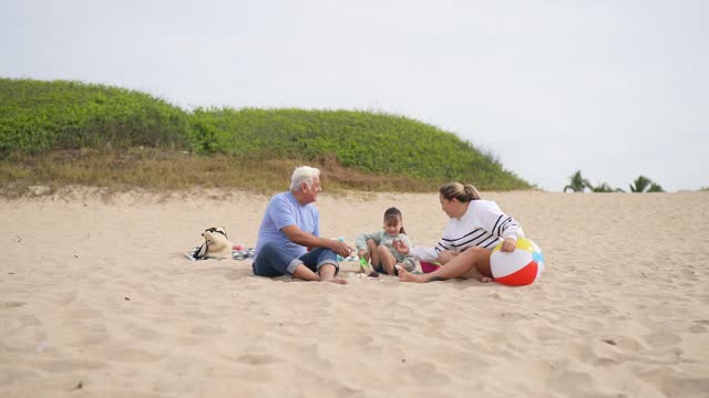 Family playing sand and talking at beach
