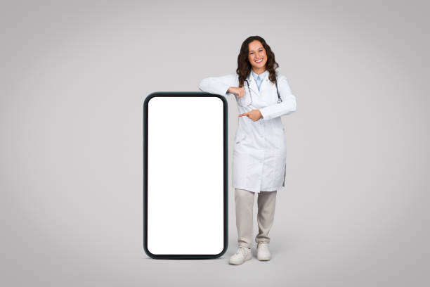 istock Happy female doctor pointing at blank smartphone screen 1995278697