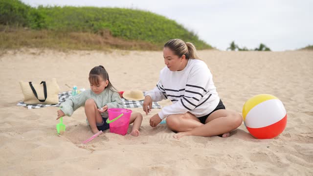 Mother playing sand with daughter at beach