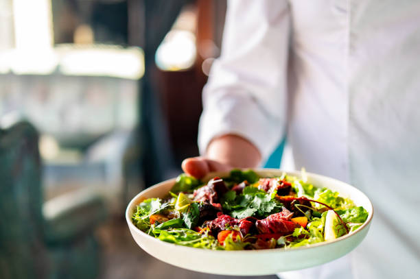 istock Men's chef or waiter hands hold a Roastbeef salad with vegetables on plate 1995291183