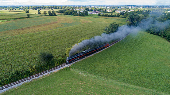 An Aerial View of a Streamlined Steam Locomotive Traveling Around a Curve, Blowing Lots of Smoke on a Sunny Summer Day